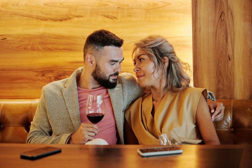 A loving couple sharing a romantic moment with red wine in a stylish restaurant.